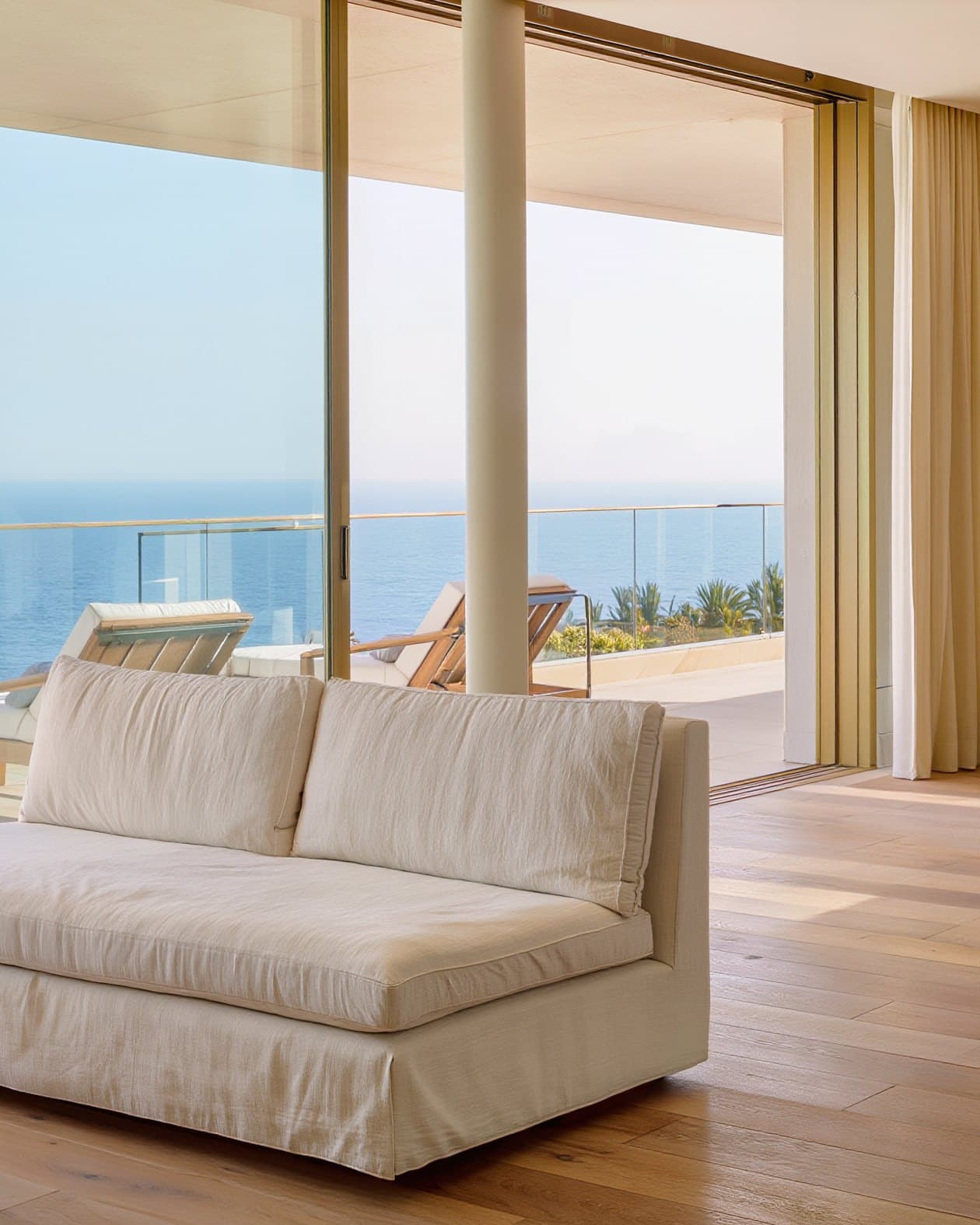Salón luminoso con sofá de lino y terraza con vistas al mar
